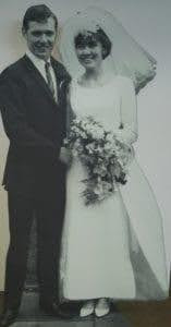 Vintage wedding photo of a smiling bride and groom holding a bouquet